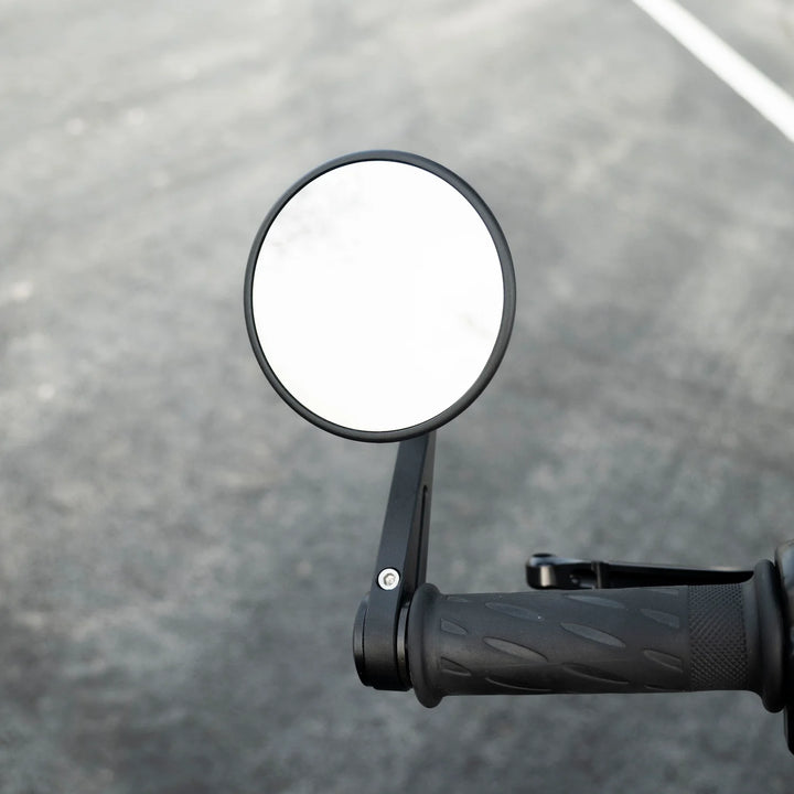 Close-up of a black BONVENT round bar-end mirror mounted above a motorcycle handlebar grip and brake lever.