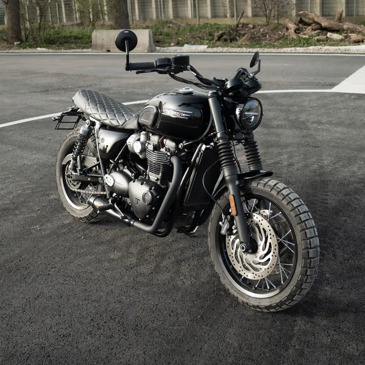 Front three-quarter view of a black Triumph motorcycle fitted with a low-profile black seat featuring diamond stitching.